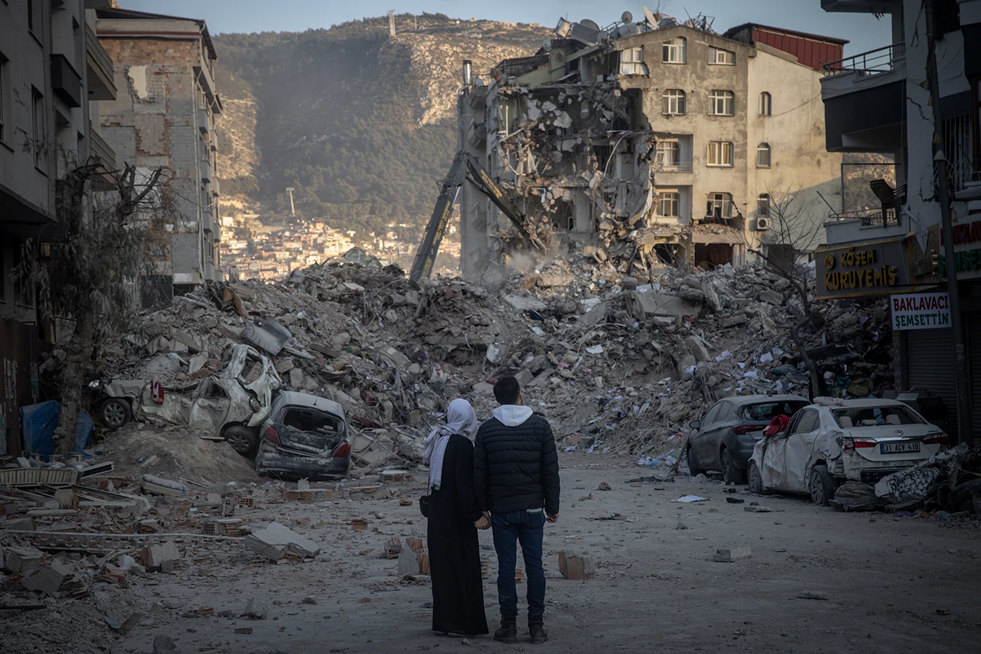 Пара смотрит на разрушенные землетрясением здания в Хатае, Турция