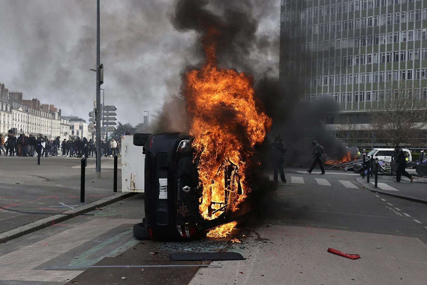 Перевернутый автомобиль горит во время демонстрации против пенсионной реформы во Франции, Нант, 28 марта 2023 года