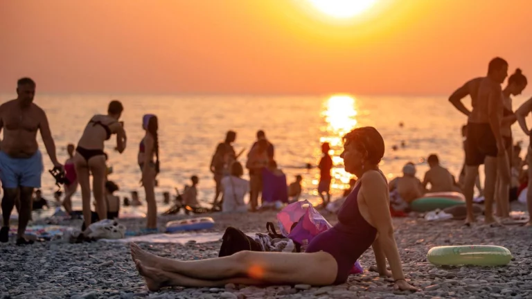 Отдыхающие на берегу Черного моря на пляже «Ривьера» на закате солнца. Сочи, Краснодарский край, Россия, июль 2025 года