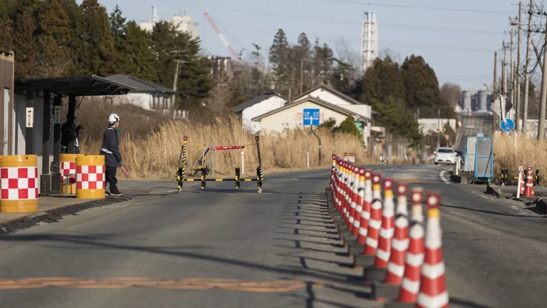 Архивное фото. Сотрудники службы безопасности, на контрольно-пропускном пункте, на заднем плане которого видна часть атомной электростанции «Фукусима-1», в городе Окума
